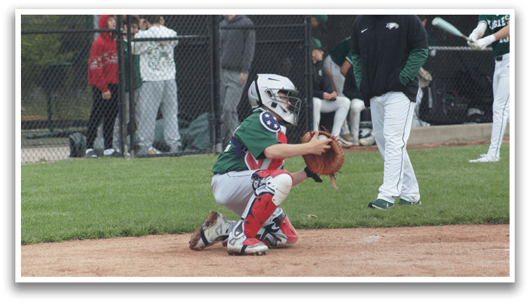A boy wearing a green shirt and red pants is playing baseball. Description generated by AI