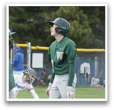 A baseball player in a green and white uniform is standing on the field. Description generated by AI