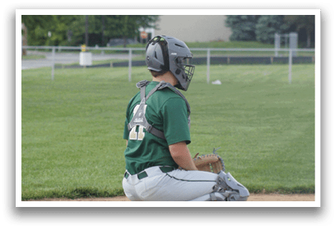A baseball player in a green shirt and white pants is pitching a ball. Description generated by AI