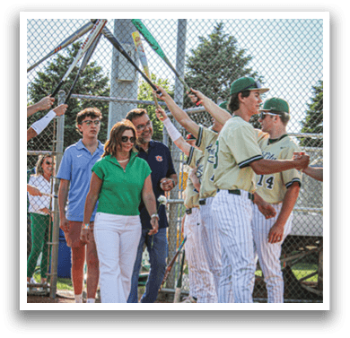 A baseball player in a green and gold uniform is throwing a ball. Description generated by AI