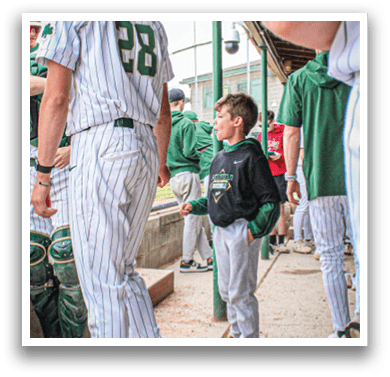 A baseball player wearing a white uniform and green sleeves is throwing a ball. Description generated by AI