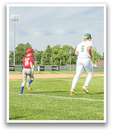 A boy wearing a grey shirt and white pants is holding a baseball. Description generated by AI