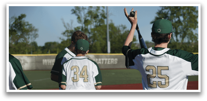 A baseball player wearing a green and white uniform is sitting on the ground with a catcher's mitt on his left hand. Description generated by AI