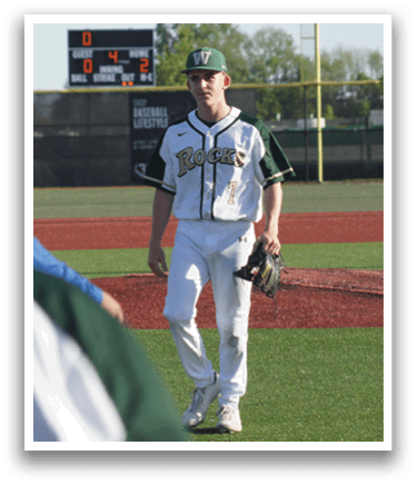 A baseball player in a green shirt and white pants is throwing a ball. Description generated by AI