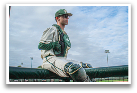 A man wearing a baseball uniform is sitting on a bench. Description generated by AI
