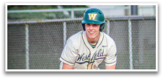 A baseball player in a white uniform is crouched down on the field. Description generated by AI