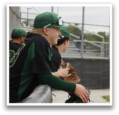 A baseball player sitting on a bench with a green and black jersey. Description generated by AI