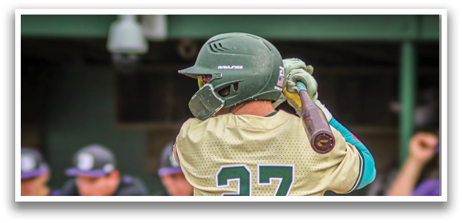 A baseball player wearing a green helmet and gold jersey. Description generated by AI