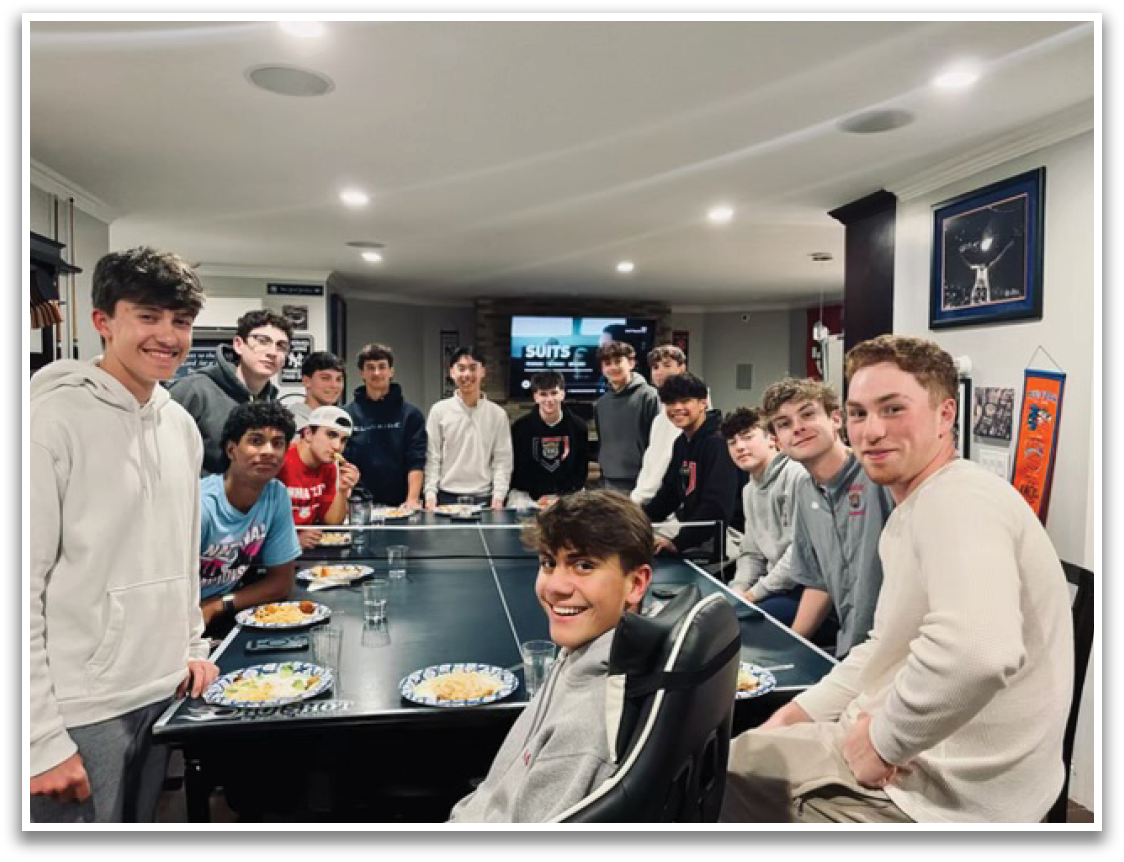 A group of people sitting around a table with plates of food. Description generated by AI