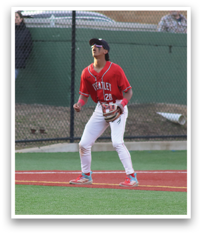 A baseball player is standing on the field, wearing a red shirt and white pants. He is holding a baseball bat and appears to be ready to hit the ball. There are several other people in the background, possibly watching the game or waiting for their turn to play. AI generated content