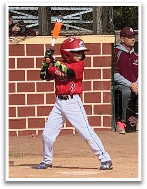 A young boy is holding a bat and getting ready to swing at a ball. Description generated by AI