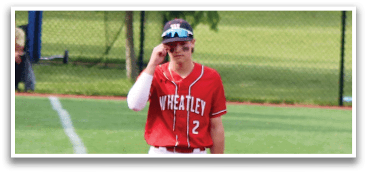 A baseball player wearing a red shirt and white pants standing on a baseball field. Description generated by AI