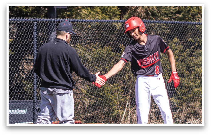 Two men shaking hands on a baseball field. Description generated by AI