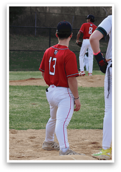 A baseball player wearing a red shirt and white pants. Description generated by AI