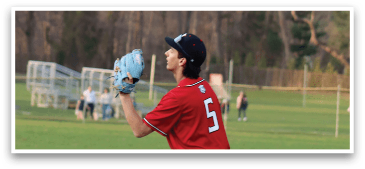 A baseball player wearing a red shirt and white pants is holding a blue baseball glove. Description generated by AI