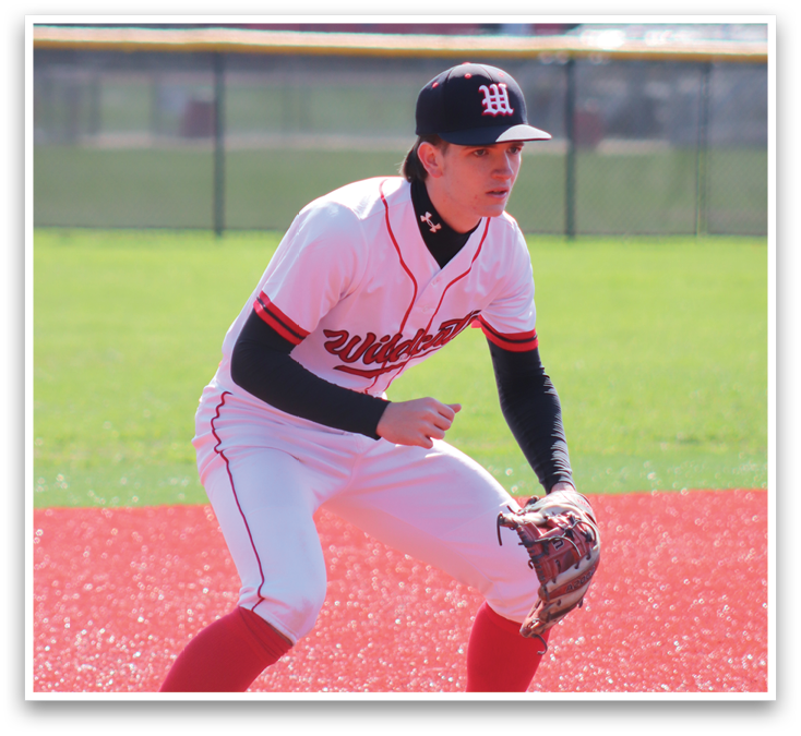 A baseball player in a white and red uniform is kneeling on the ground. Description generated by AI
