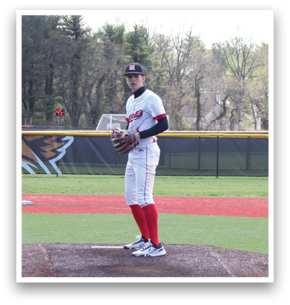 A baseball player in a white and red uniform stands on a pitcher's mound. Description generated by AI