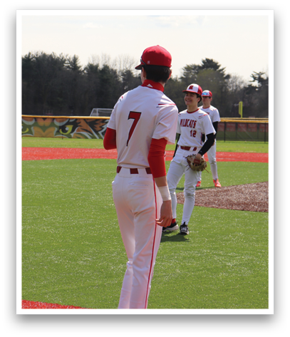 A baseball player wearing a red and white uniform stands on the field. Description generated by AI