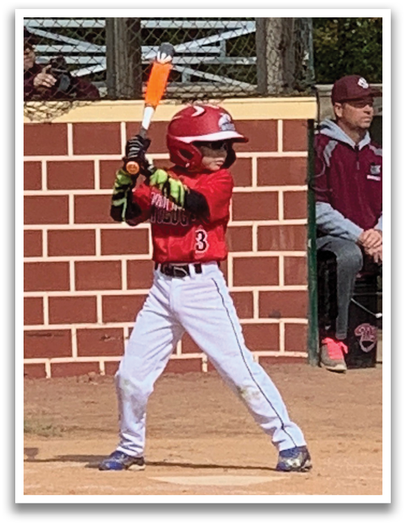 A young boy is holding a bat and getting ready to swing at a ball. Description generated by AI