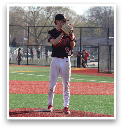 A baseball player in a black shirt and white pants is on the pitcher's mound. Description generated by AI