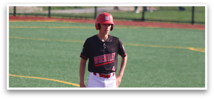 A boy wearing a red helmet and black shirt stands on a baseball field. Description generated by AI