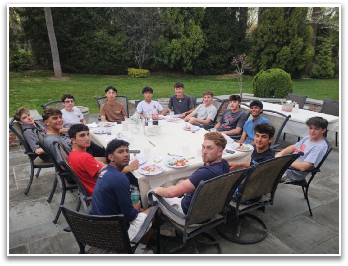 A group of people sitting around a table outside. Description generated by AI