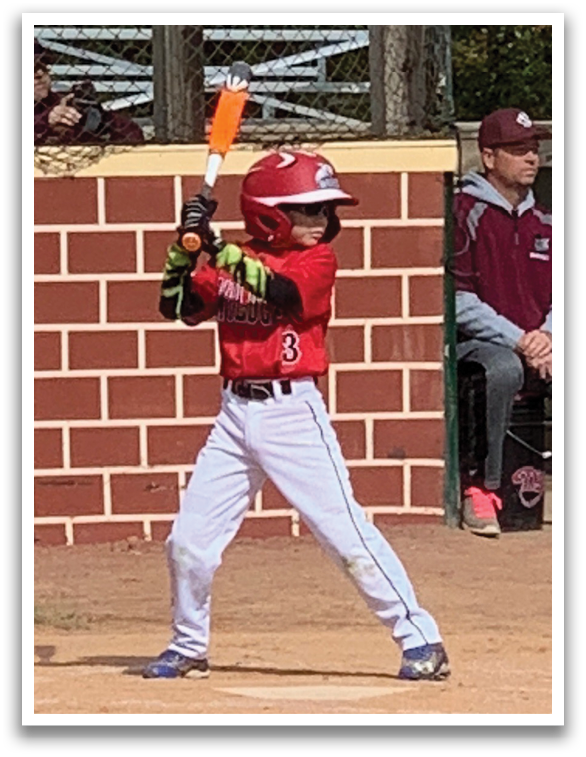 A young boy is holding a bat and getting ready to swing at a ball. Description generated by AI