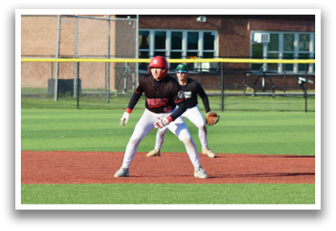 A baseball player in a black shirt and red helmet is standing on the field. Description generated by AI