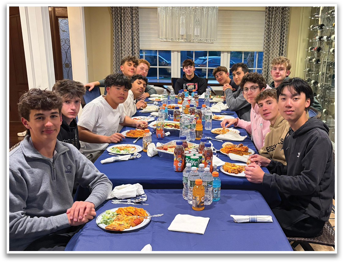 A group of people are sitting around a table with food and drinks. Description generated by AI