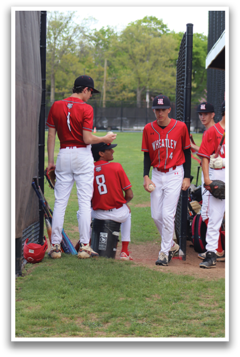 A group of baseball players standing in the grass. Description generated by AI