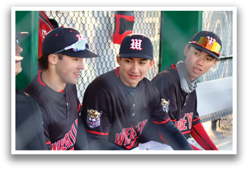 A baseball player in a black shirt and red helmet is standing on the field. Description generated by AI