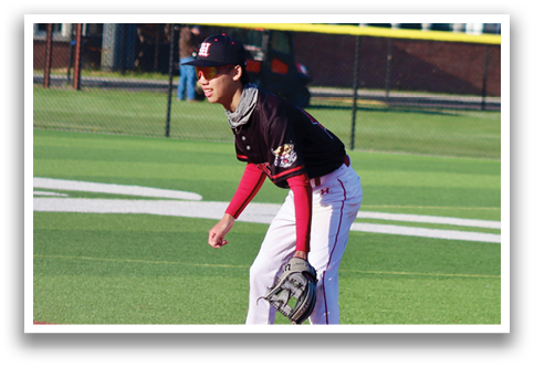 A baseball player in a black shirt and red helmet is standing on the field. Description generated by AI