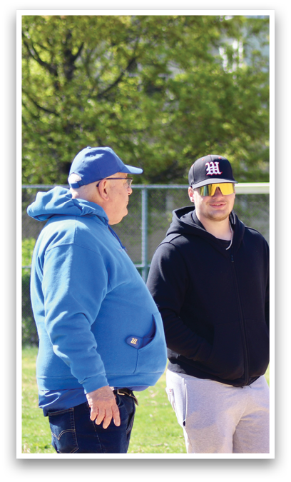 Two men standing on a baseball field. Description generated by AI