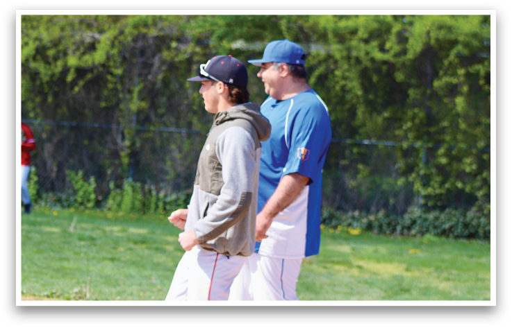 Two men standing on a baseball field. Description generated by AI