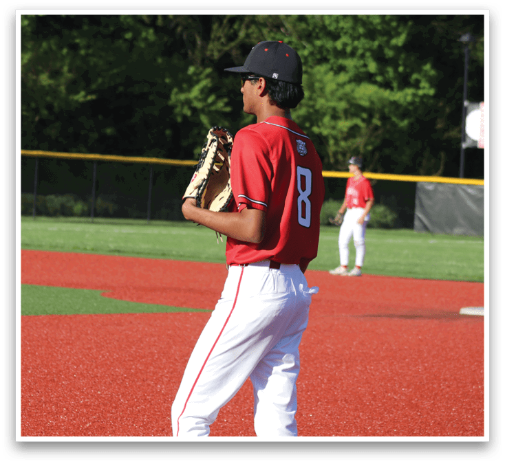 A baseball player wearing a red shirt and white pants is holding a baseball glove. Description generated by AI