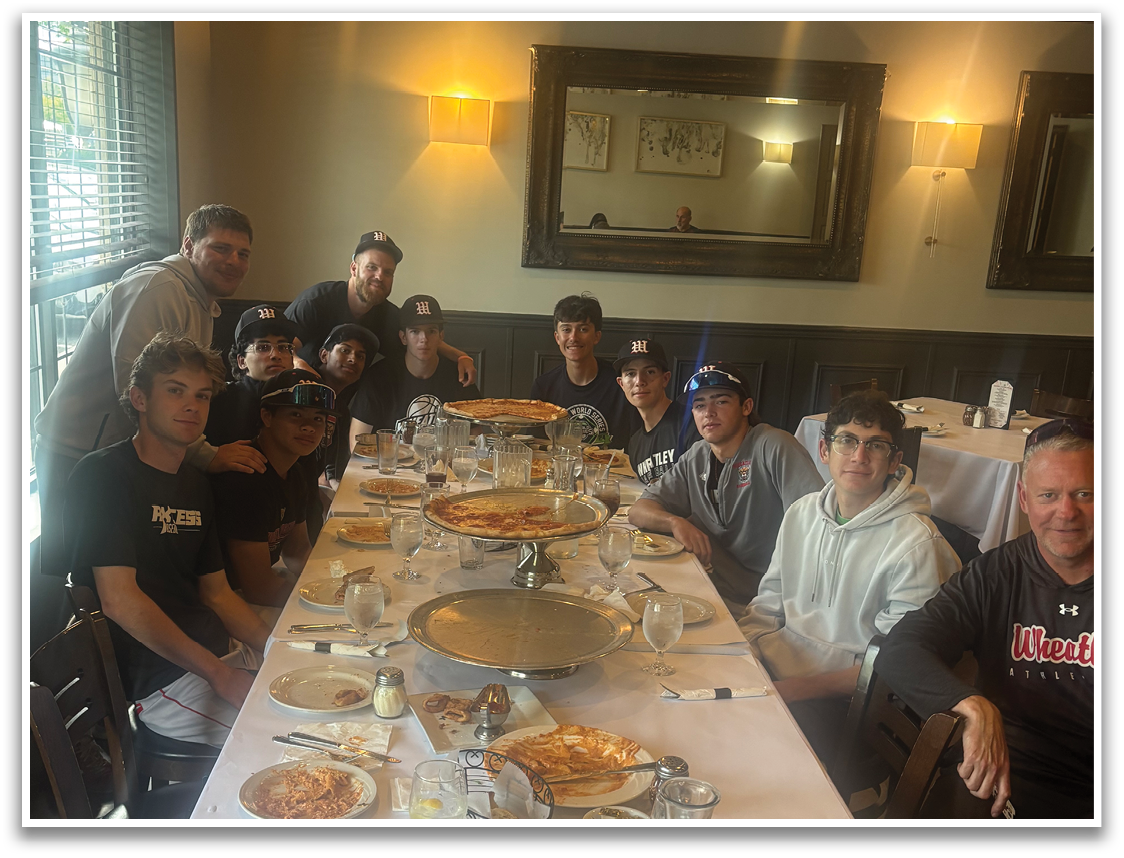 A group of people sitting around a table with pizza. Description generated by AI