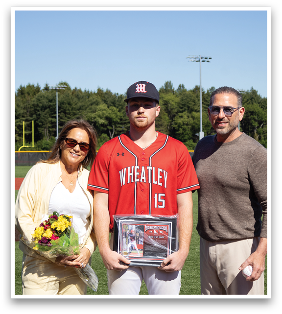 A man holding a baseball trophy with a woman and a man in a sweater. Description generated by AI