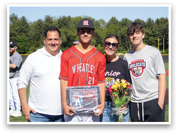 A man holding a baseball trophy with his family. Description generated by AI