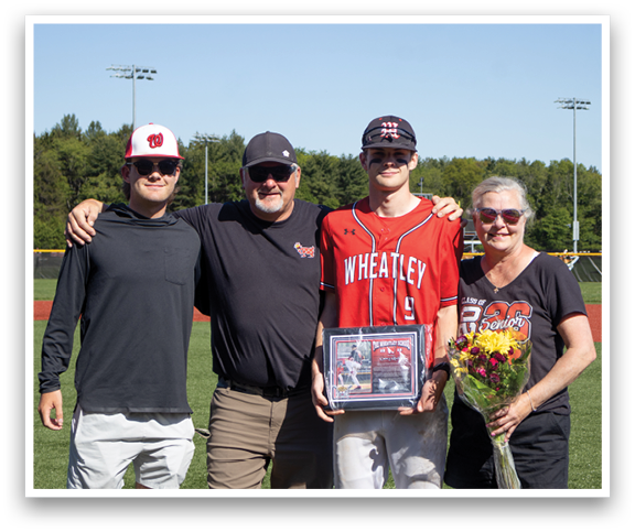 A man holding a baseball trophy with his family. Description generated by AI