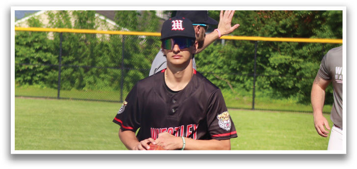 A baseball player wearing a black shirt and white pants. Description generated by AI