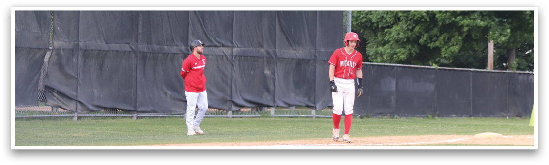 A baseball player in a red shirt and white pants standing on a field. Description generated by AI