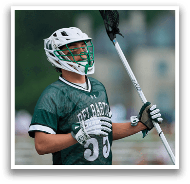 A man wearing a green and white uniform is holding a lacrosse stick. AI generated content