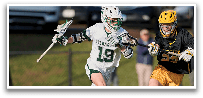 Two men are playing a game of lacrosse on a field. One man is running with a lacrosse stick, while the other is running with a stick and a ball. They are both wearing uniforms. AI generated content