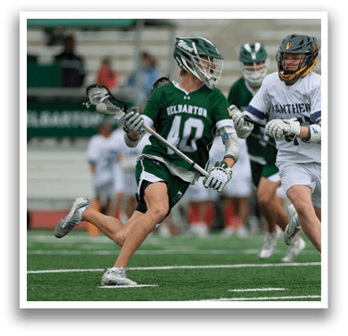 Two men playing lacrosse on a field. One man is wearing a green and white uniform and the other is wearing a white uniform. AI generated content