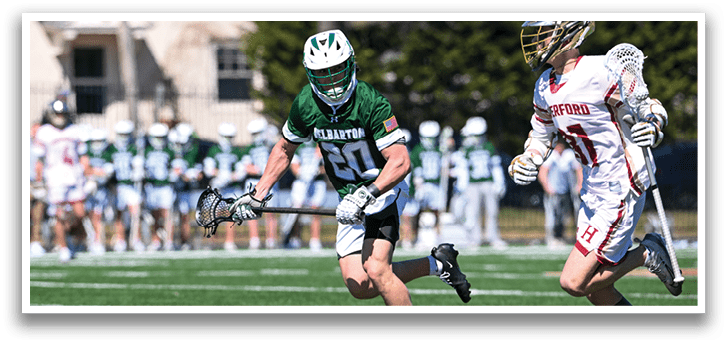 Two men are playing lacrosse on a field. One man is running with a lacrosse stick, while the other man is running with a stick and a helmet. AI generated content
