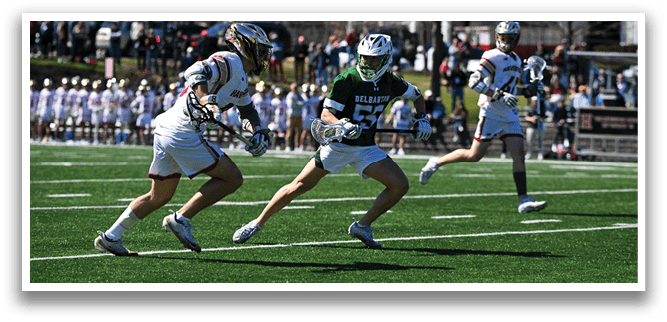 Two men are playing a game of lacrosse on a field. One player is running with a stick, while the other is chasing him. There are several other people on the field, some of whom are holding sticks. A car is parked in the background. AI generated content