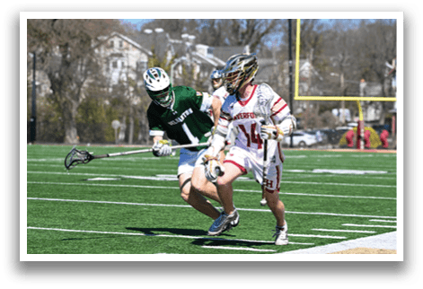 Two men playing lacrosse on a field. One man is running with a stick, while the other is trying to stop him. AI generated content
