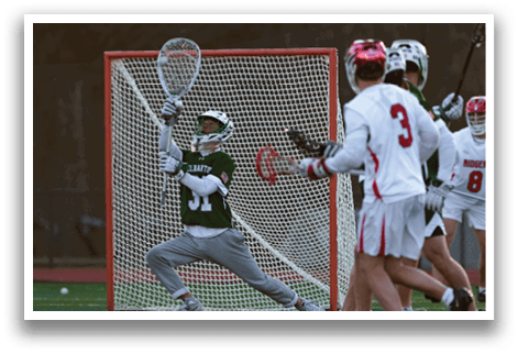 A lacrosse player in a green and white uniform is attempting to block a shot on goal. AI generated content