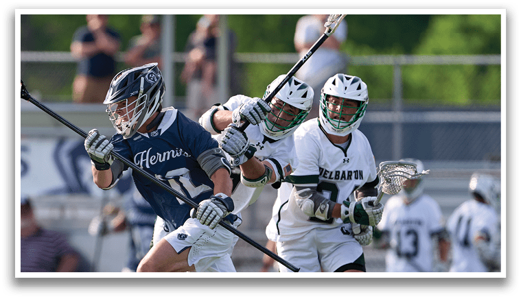 A man in a blue and white uniform is running with a lacrosse stick. Description generated by AI