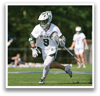 A man wearing a white shirt and green and white shorts is running on a field. Description generated by AI